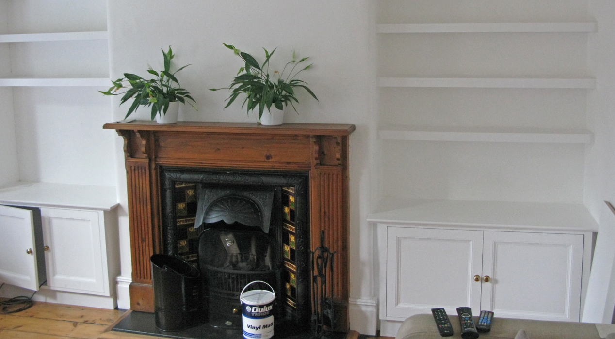 Carpentry by Haldor Construction. Bookshelves and built in cupboards either side of a Victorian fireplace.
